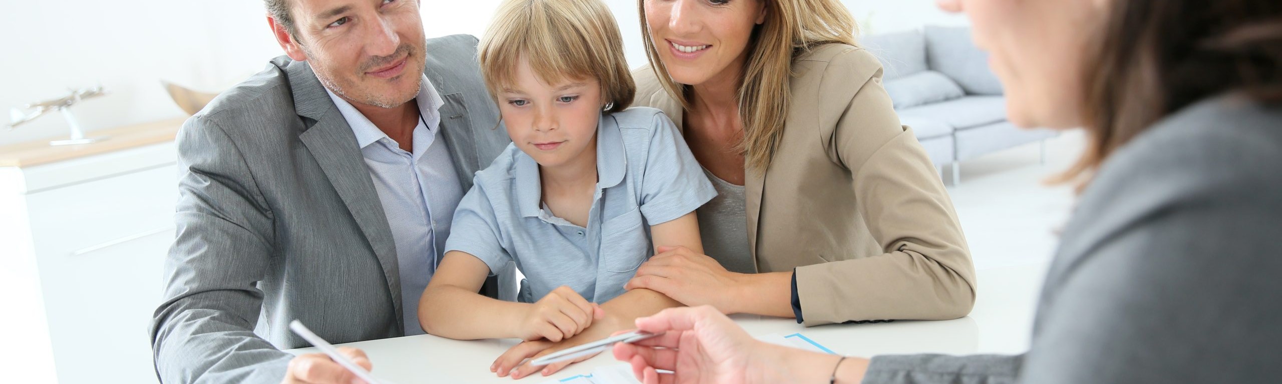 Dad, son, and mom signing papers at a meeting to buy new home